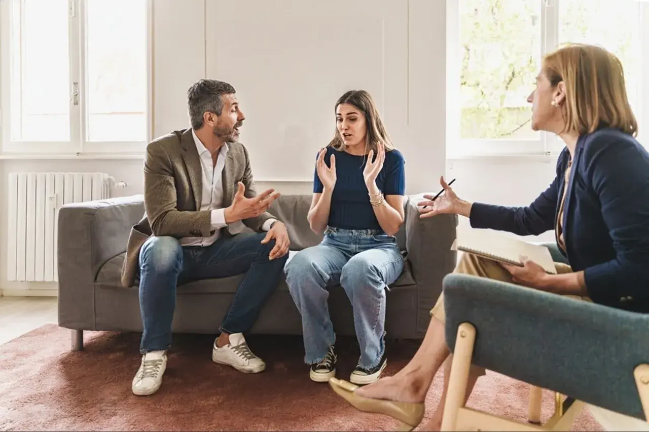 Un couple en thérapie, discutant de problèmes familiaux et d'abus de faiblesse. La thérapeute écoute attentivement.