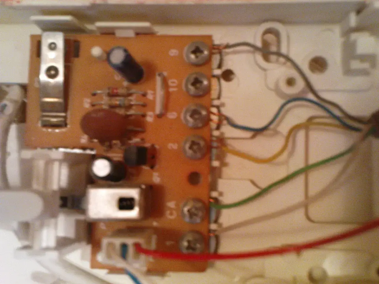 Wnętrze unifonu z widoczną płytką drukowaną, elementami elektronicznymi i przewodami.