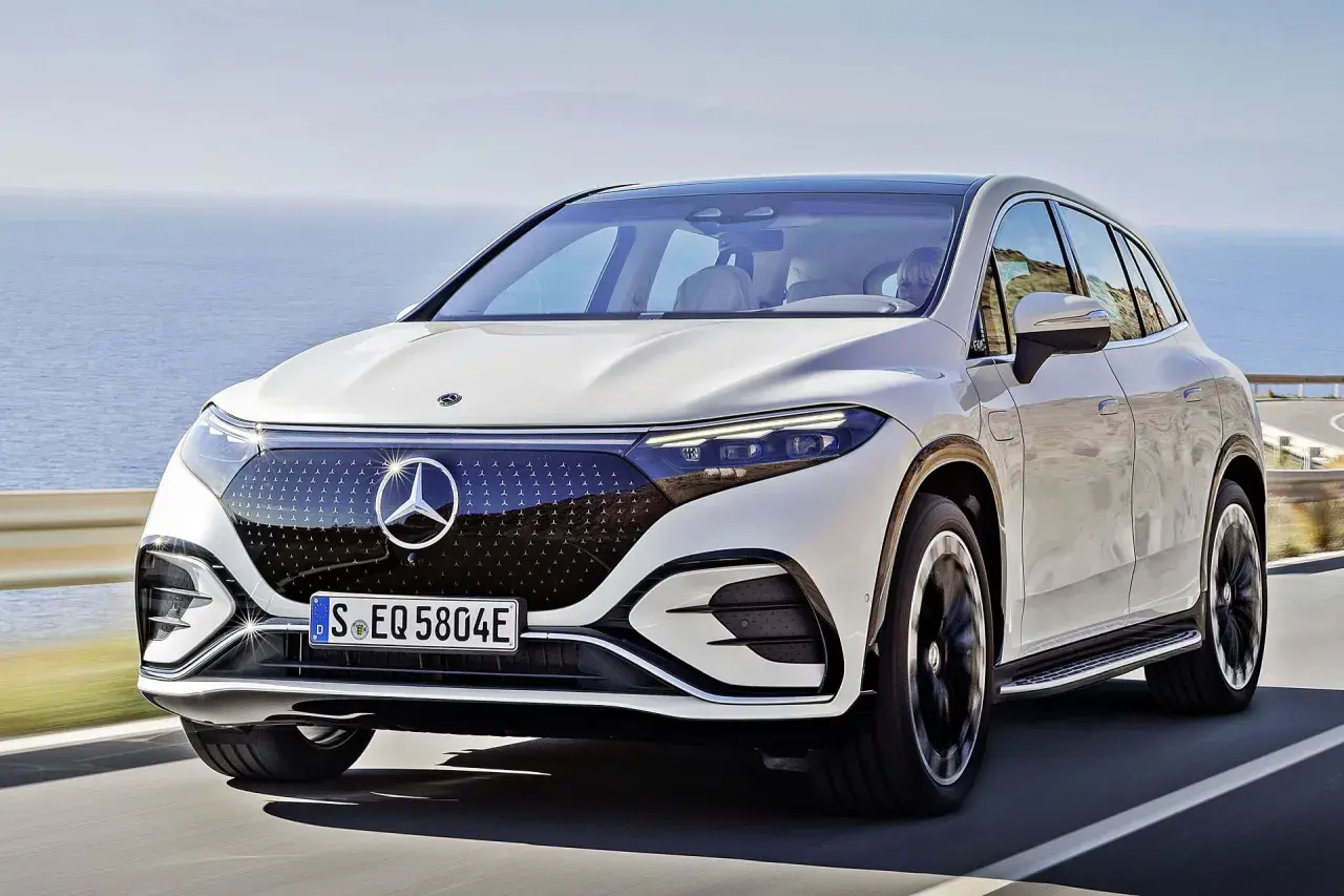 Biały Mercedes EQS SUV jedzie wzdłuż malowniczego wybrzeża.