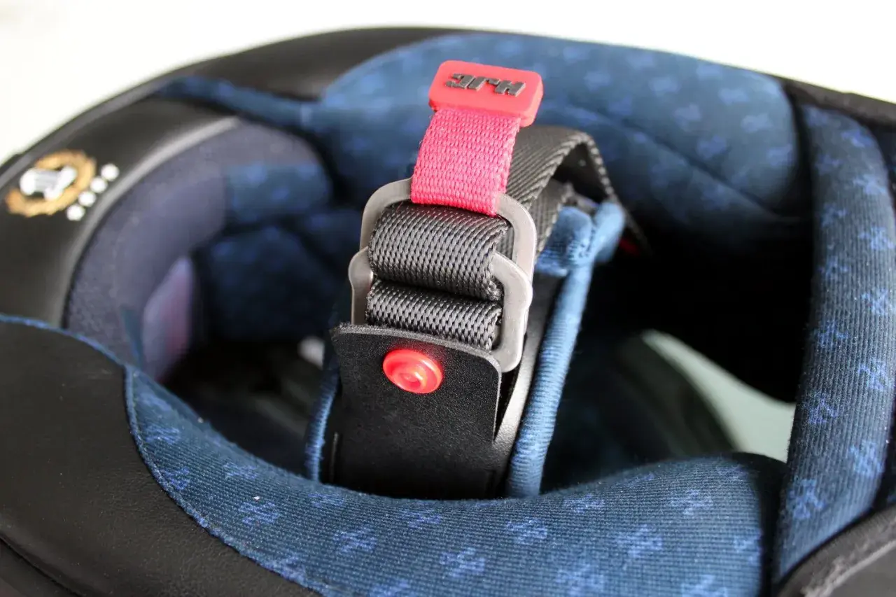 Detalle de los tipos de cierre de casco de moto: correa con hebilla de liberación rápida y logo HJC.