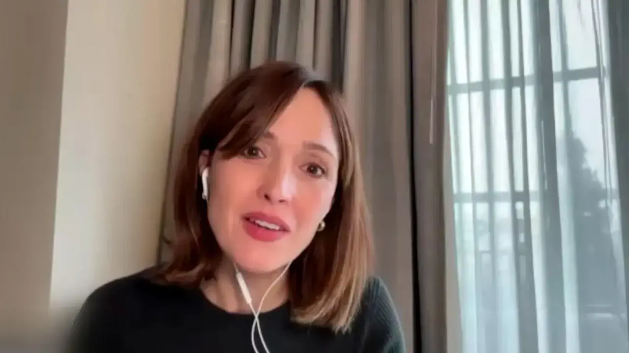 Rose Byrne w jednym ze swoich filmów, w białych słuchawkach, z uśmiechem na twarzy.