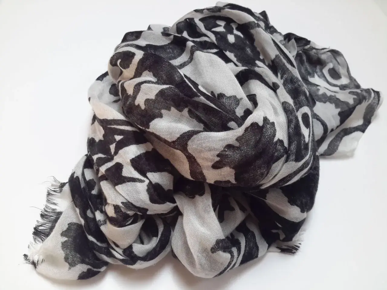 Ein leicht zerknitterter Schal aus Polyester-Plastik mit einem auffälligen schwarz-weißen Blumenmuster.