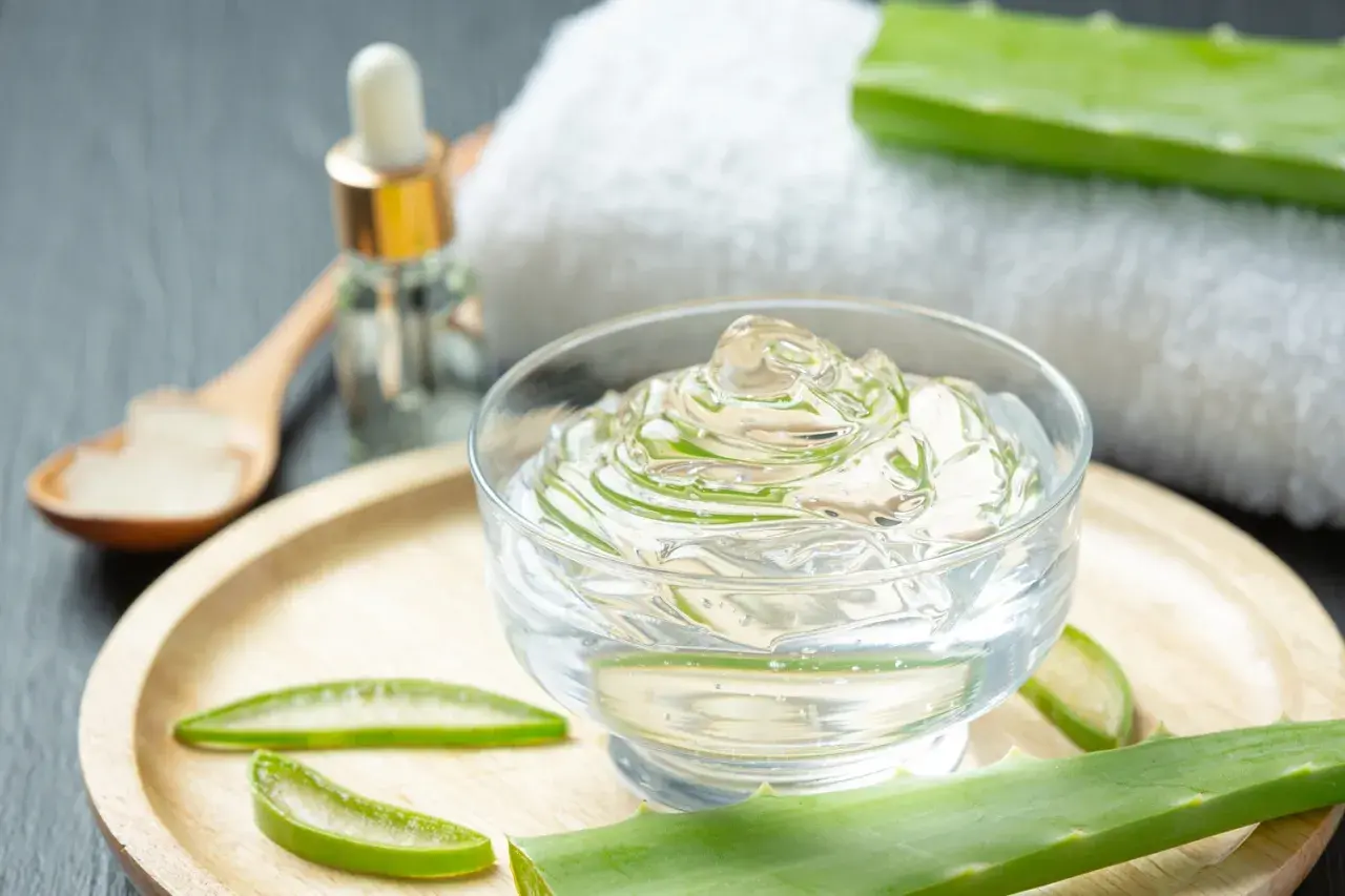 Przezroczysty żel z aloesu, liście aloesu i buteleczka z pipetką. Naturalny **aloe barbadensis leaf extract** do pielęgnacji.