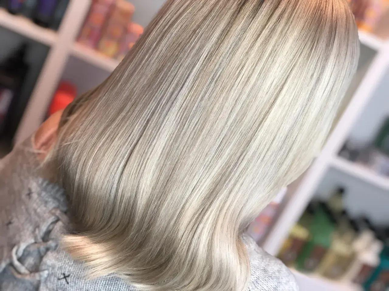 En person med vackert, ljust blondt hår som har fått en ny depend hårfärg. Håret är rakt och glansigt, med en mjuk övergång från mörkare till ljusare toner.