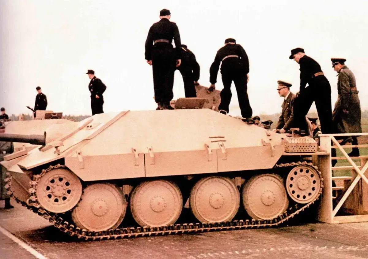 Männer in Uniformen stehen auf und neben einem hellbraunen Opel Hetzer Jagdpanzer.