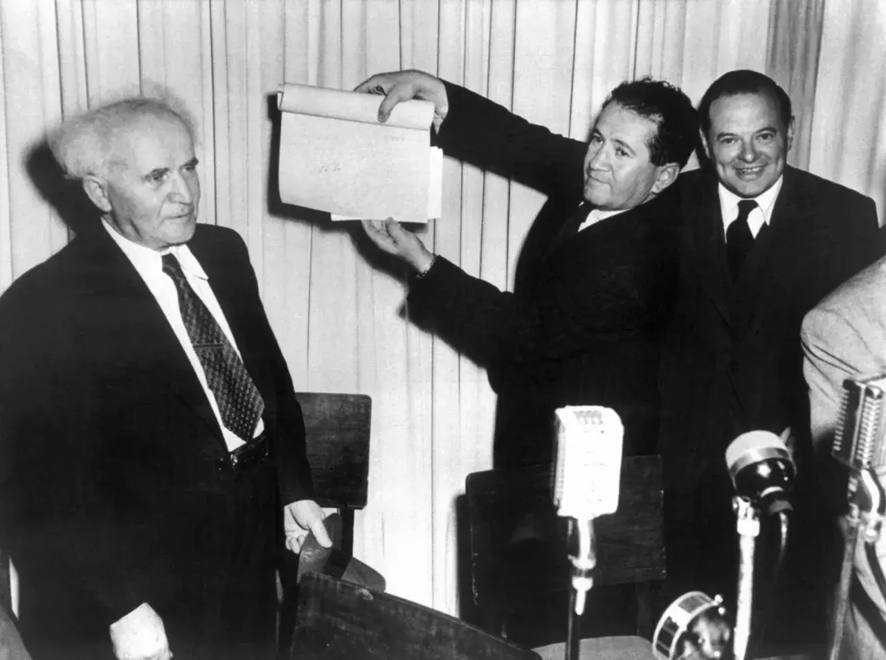 David Ben-Gurion hält ein Dokument hoch, das die Entstehung Israels symbolisiert.