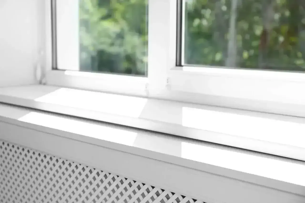 Biały parapet zewnętrzny z widocznym uszczelnieniem, chroniący przed warunkami atmosferycznymi.