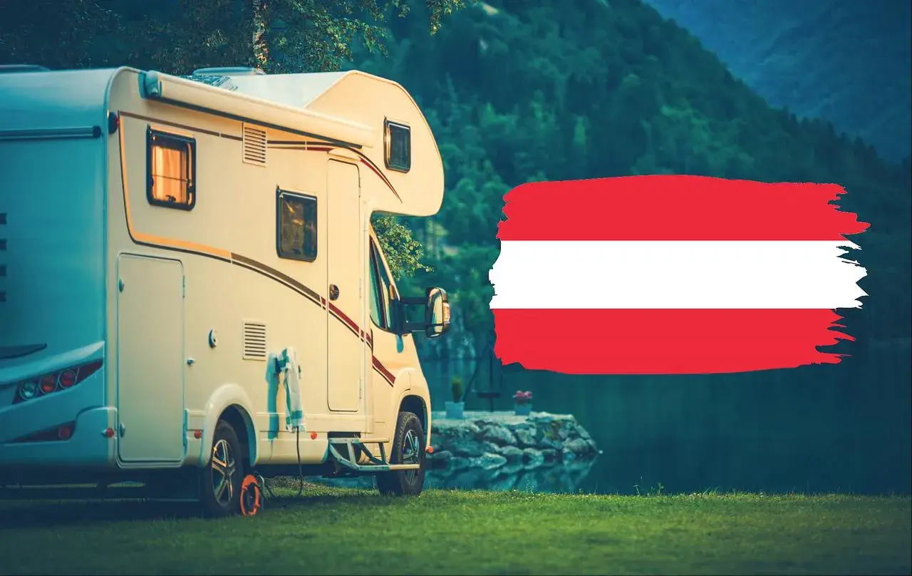 Kamper zaparkowany nad jeziorem w Karyntii, Austria. Obok flaga Austrii.