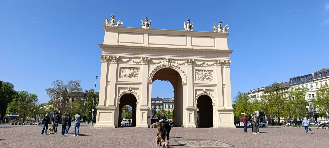 Brama Brandenburska w Poczdamie, gdzie leży to piękne miasto, z ludźmi i psami na placu.