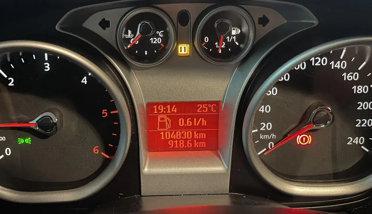 Deska rozdzielcza Ford Focus z kontrolkami: temperatura, paliwo, przebieg, prędkościomierz i kontrolka hamulca ręcznego.