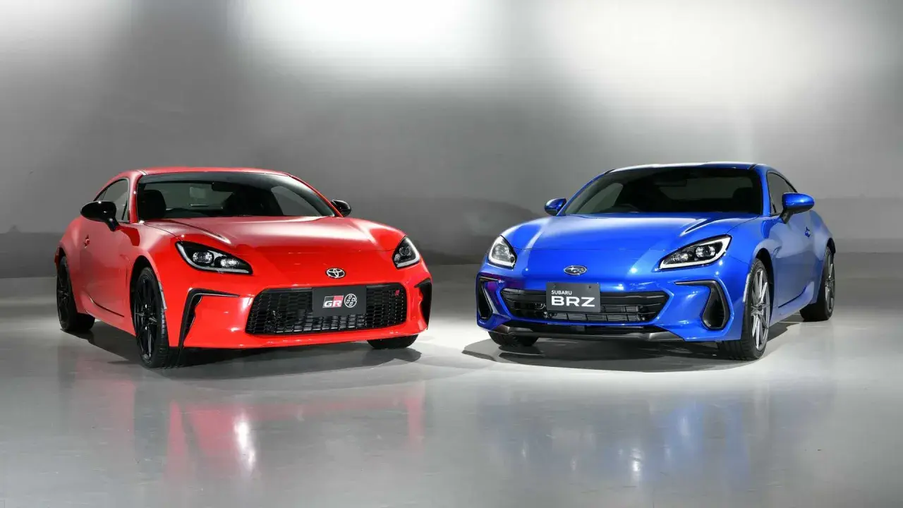 Dwa sportowe coupe, czerwona Toyota GR86 i niebieski Subaru BRZ, stoją obok siebie, gotowe do wyścigu.