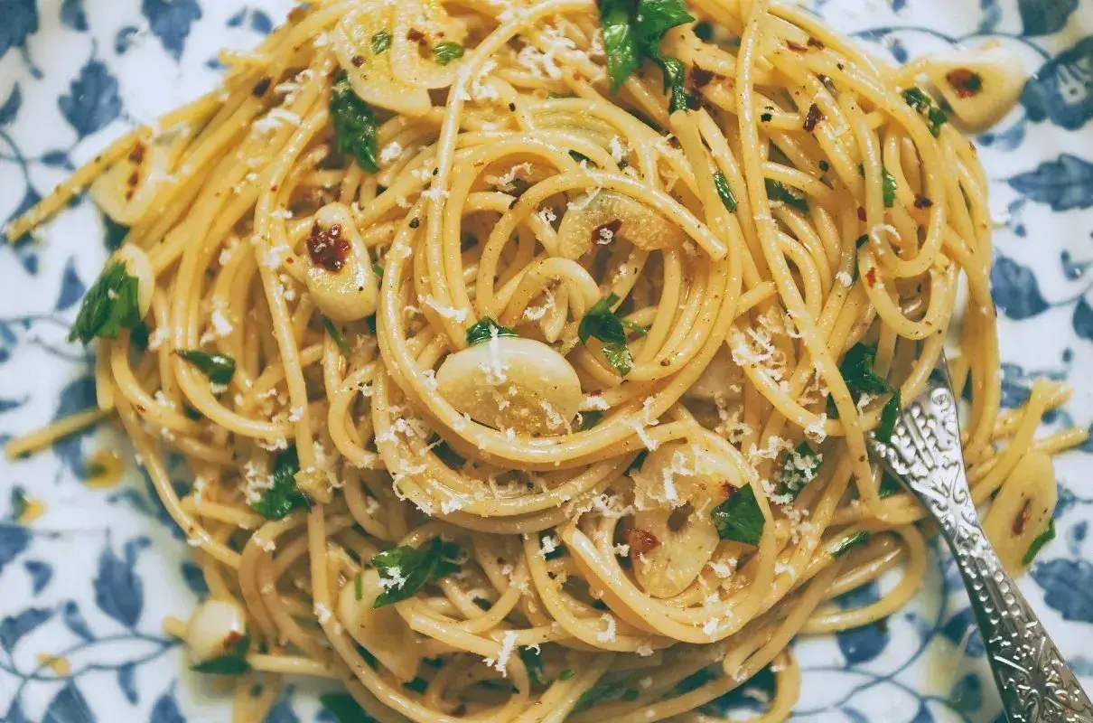 Pyszne spaghetti aglio e olio z czosnkiem, natką pietruszki i płatkami chili, posypane parmezanem.