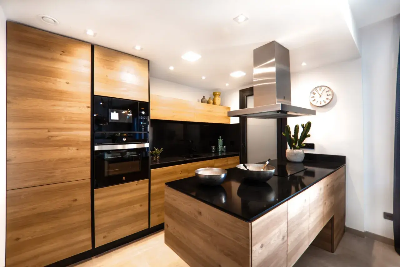 Cucina moderna con ante in legno di rovere, piano in quarzo nero e isola centrale. Un progetto per rinnovare cucina in legno con stile.
