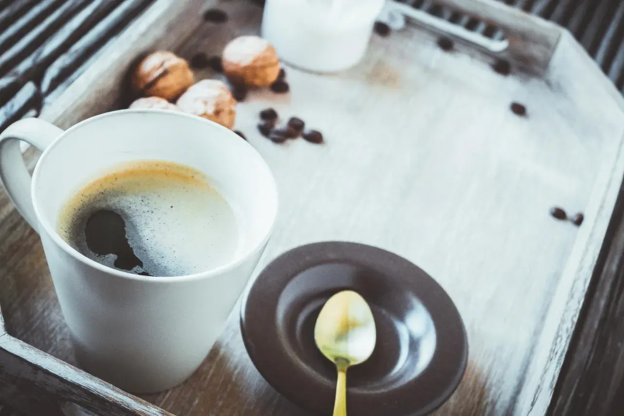 Eine Tasse schwarzer Kaffee gesund, mit Keksen und Kaffeebohnen auf einem Holzteller.