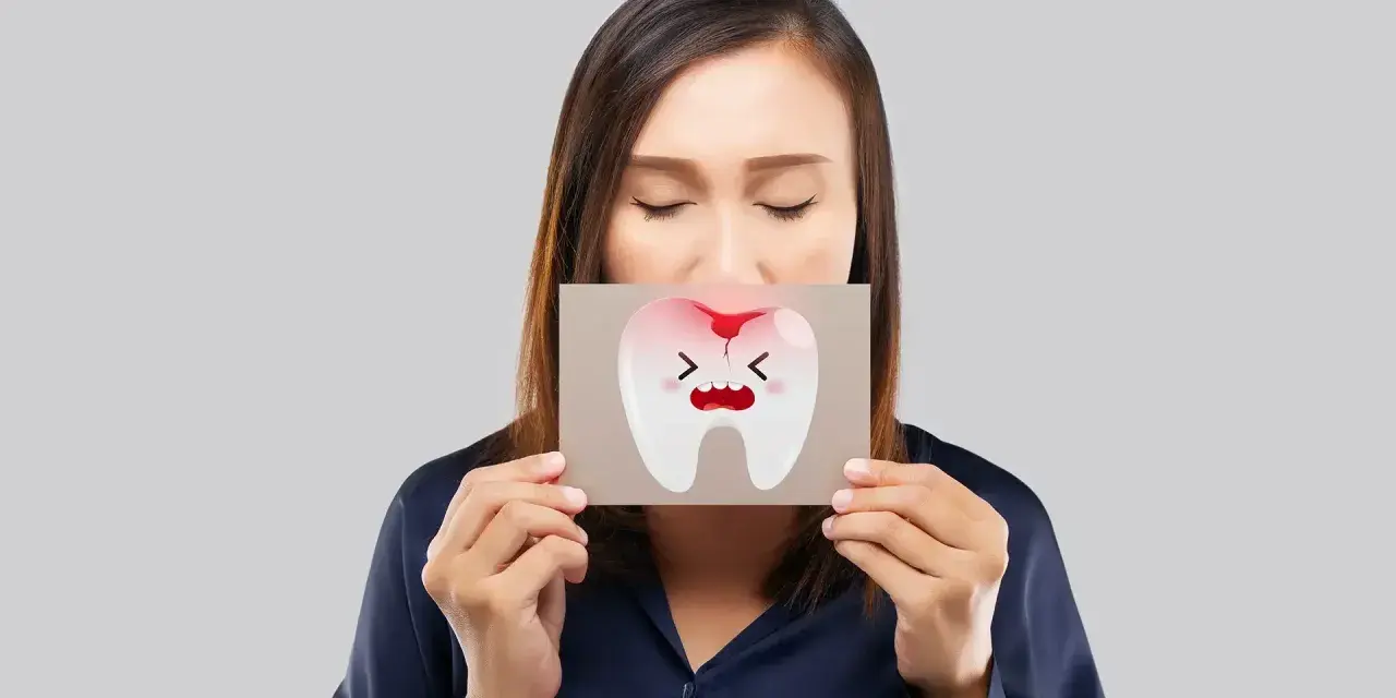 Donna con gli occhi chiusi mostra un disegno di un dente che cade, con espressione sofferente e macchie di sangue.