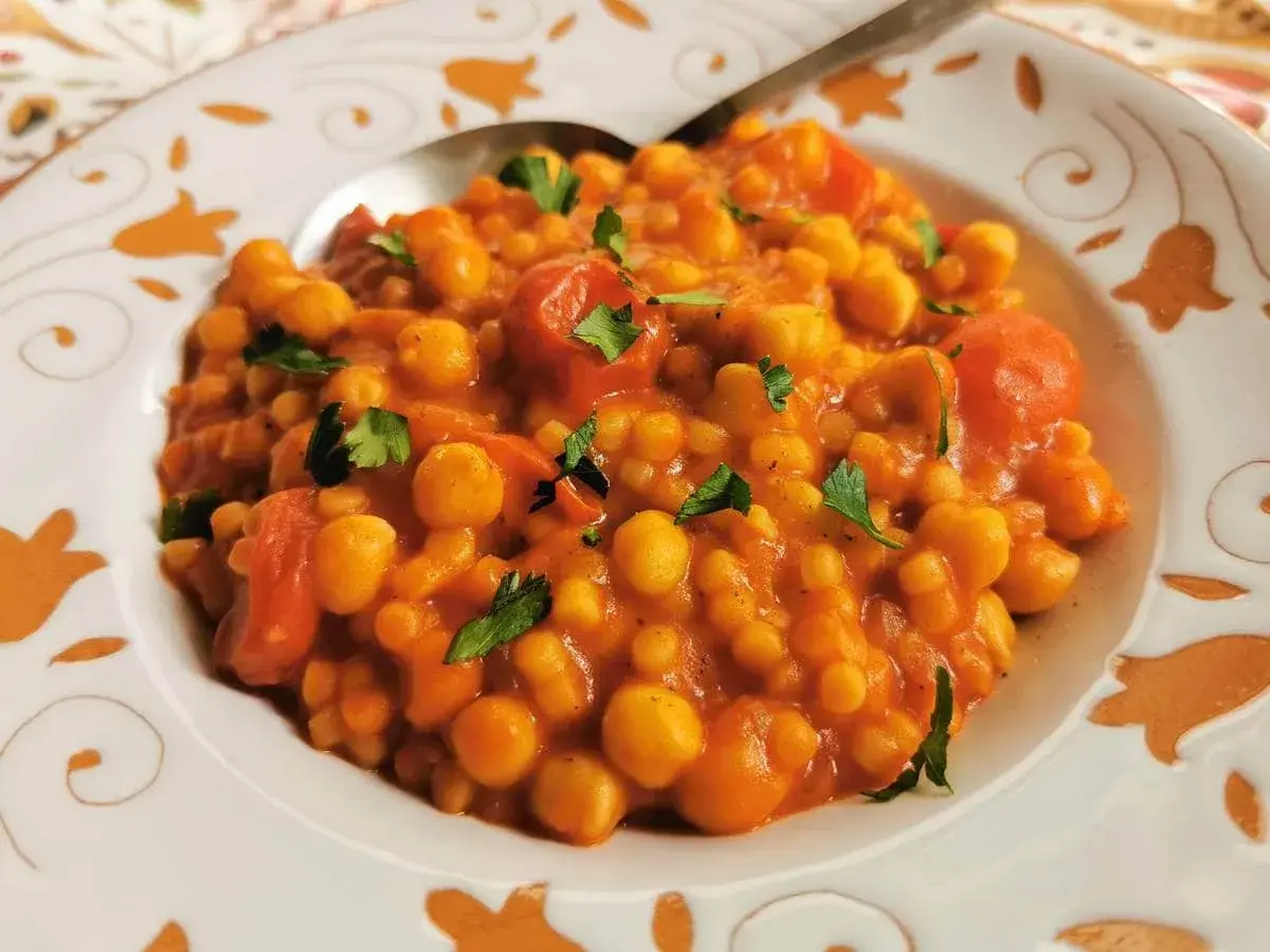 Piatto di ceci e pomodoro, guarnito con prezzemolo. Un sapore che ricorda la peretta formaggio, un classico.