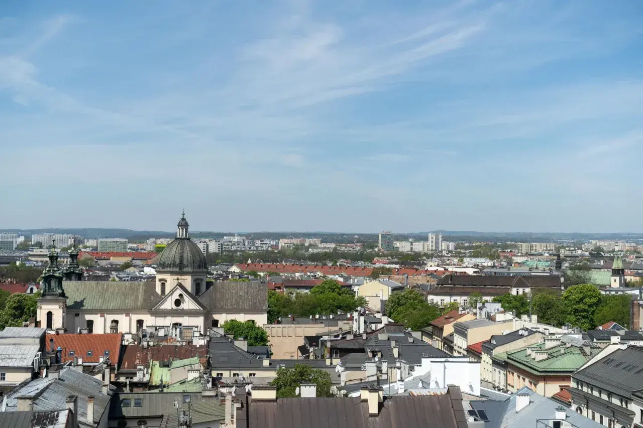 Widok na krakowskie dachy i kościół z kopułą. W tle nowoczesne budynki, które mogą wpływać na ceny mieszkań Kraków.