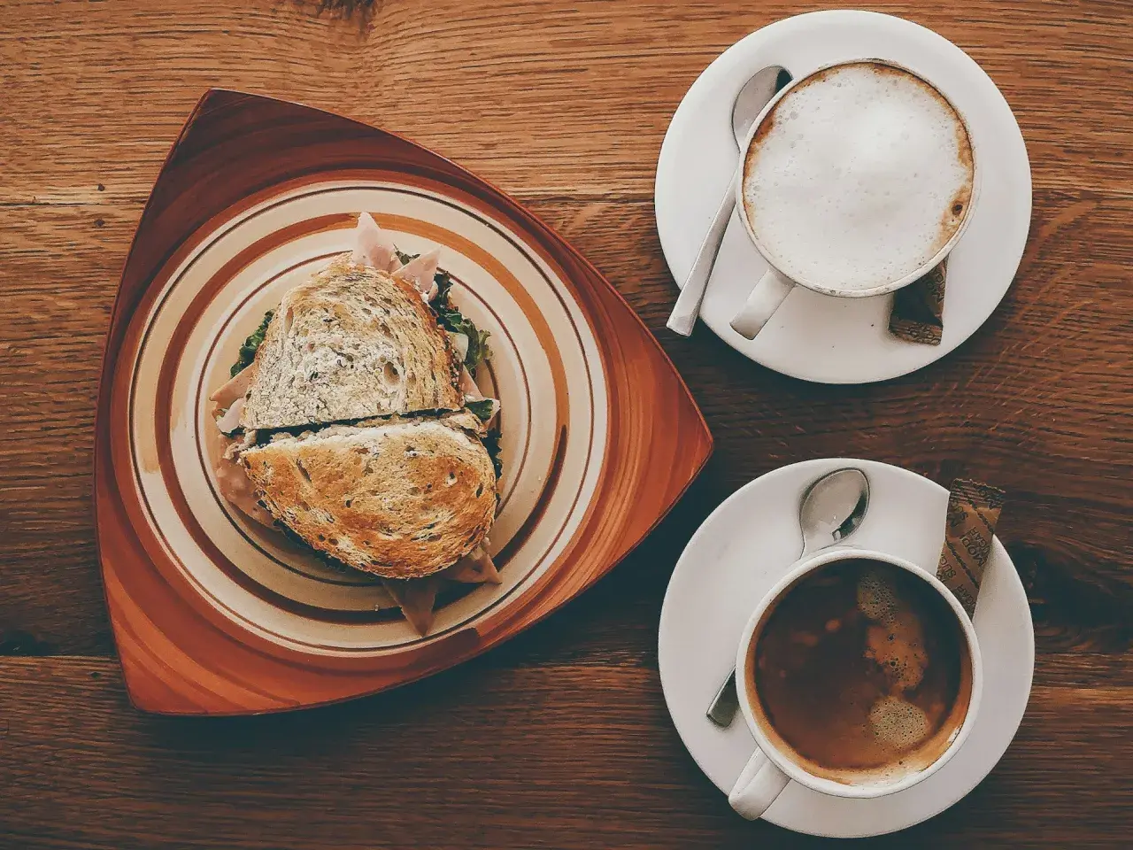 Ein Sandwich und ein Café Americano auf einem Holztisch.