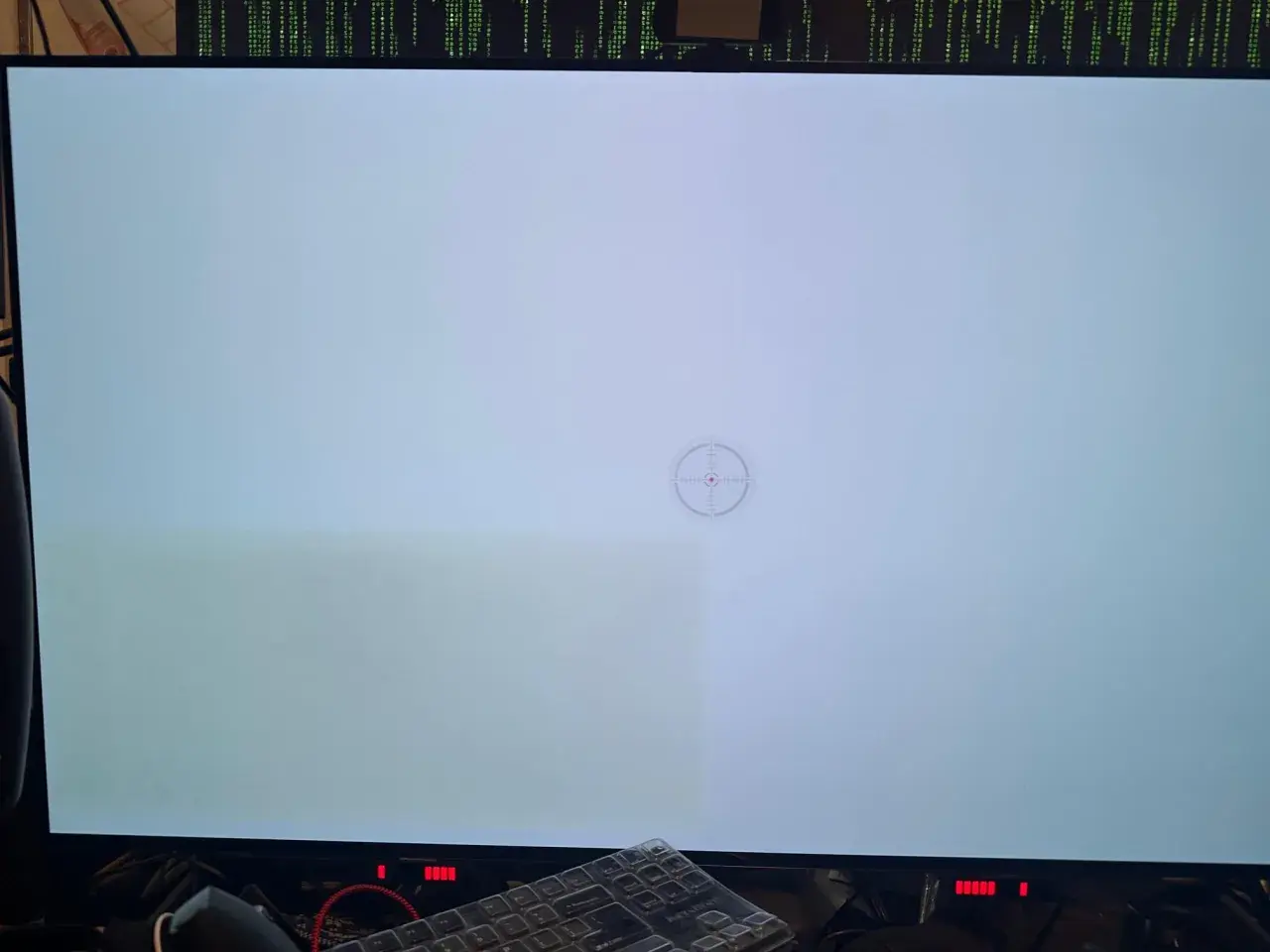 Helles Display mit sichtbaren grünen Schlieren links, ein Zeichen für OLED Burn-in. Ein Fadenkreuz-Symbol ist in der Mitte zu sehen.