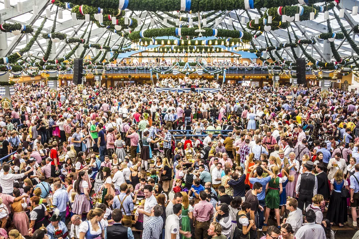 Riesiges Festzelt voller Menschen in Tracht. Die Frage "wie lang geht die Wiesn" beschäftigt viele Besucher dieses Volksfestes.