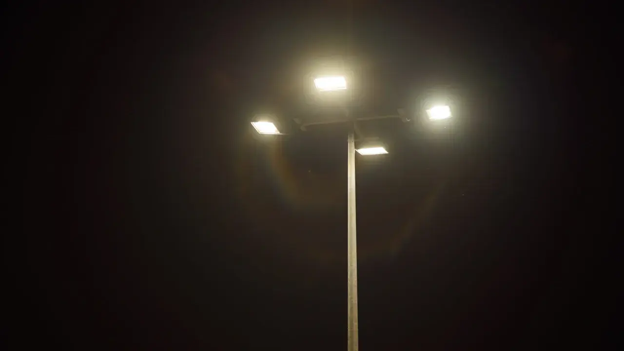 Słup oświetleniowy z czterema lampami LED, które rozświetlają noc. Widać tęczowe refleksy, jakby porównanie lampa sodowa vs led.