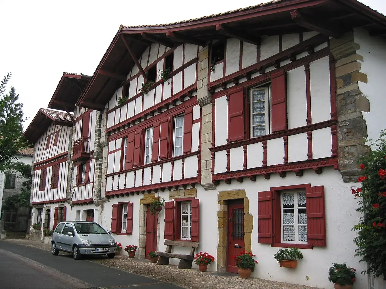 Maison basque typique, peut-être l'origine du nom Ithurburu. Volets rouges, colombages blancs, une voiture garée.