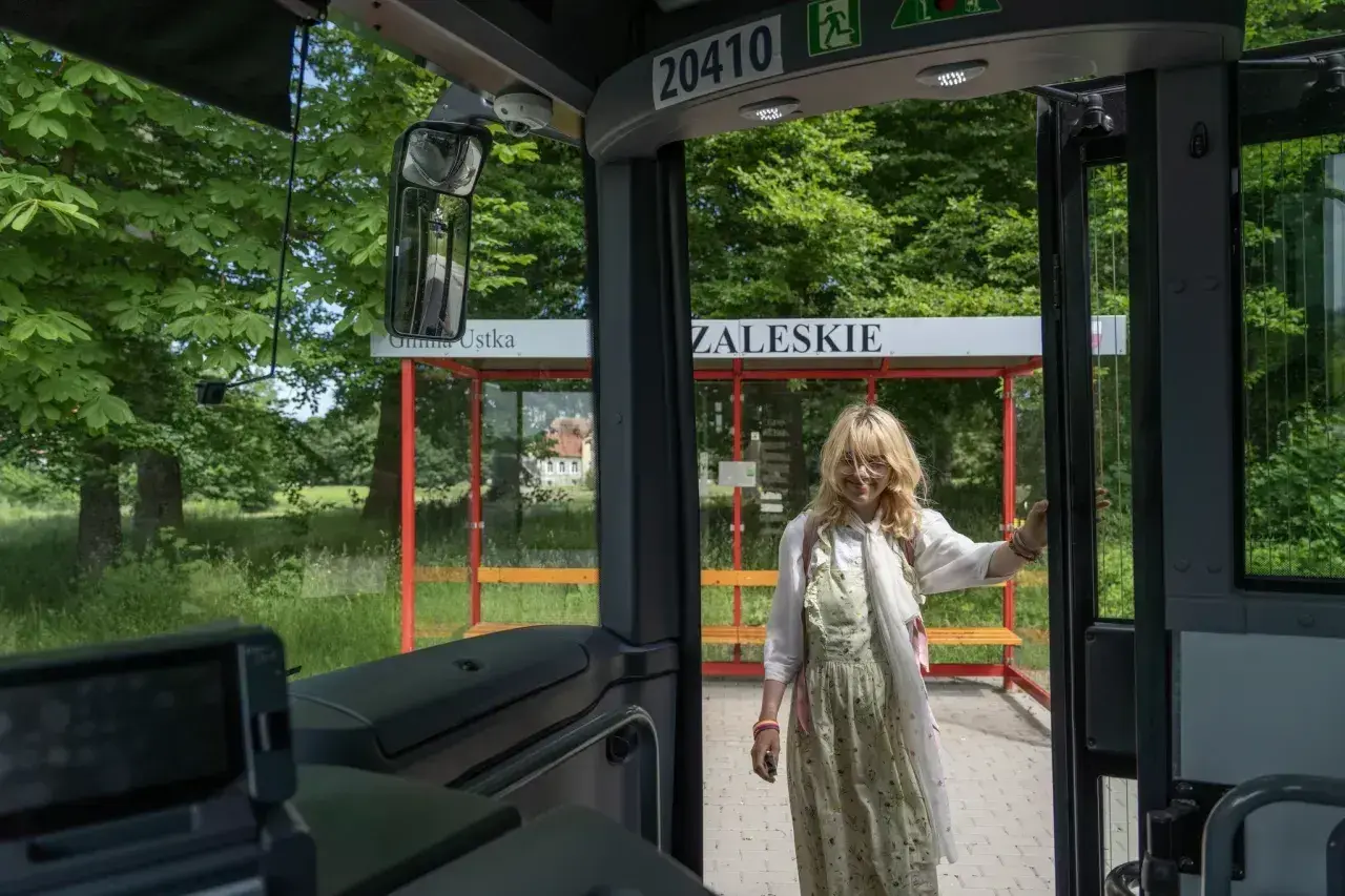 Dziewczyna wysiada z autobusu na przystanku Gmina Ustka. Słupsk i Ustka to miejsca, które warto odwiedzić.