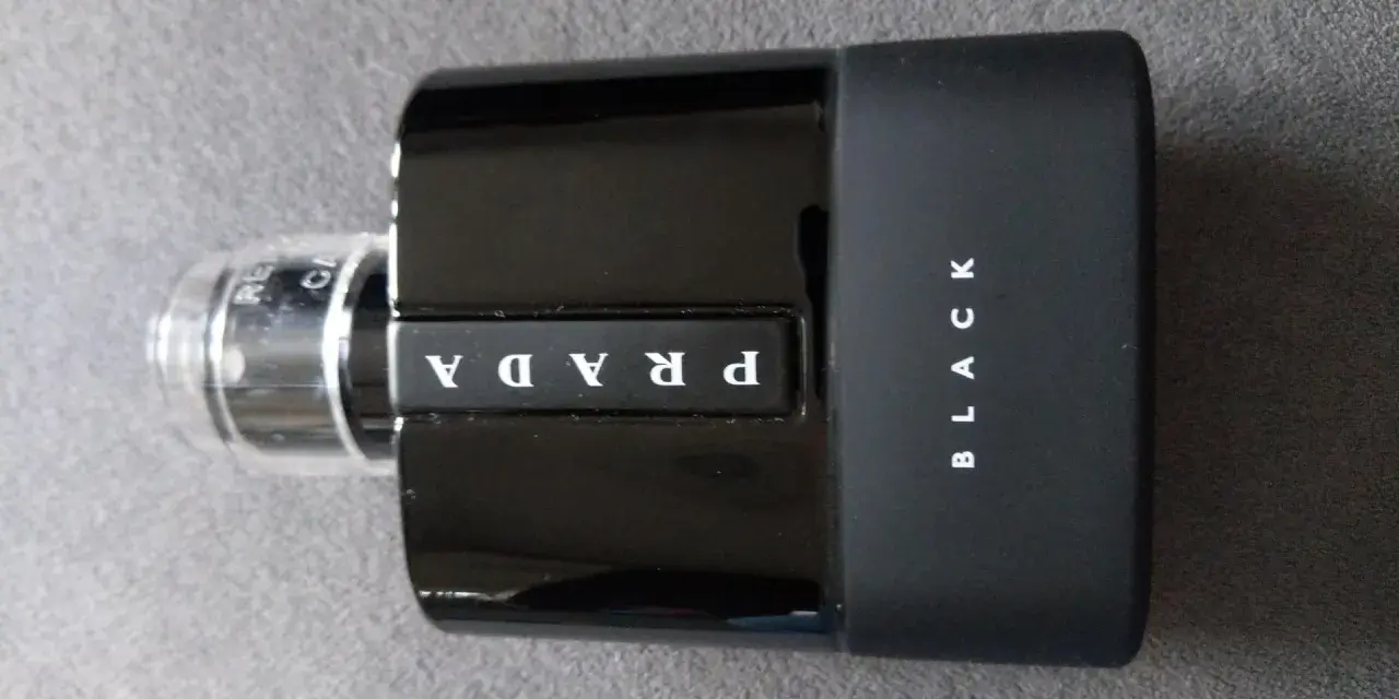 Elegancka, czarna butelka perfum Prada Black z białym logo.