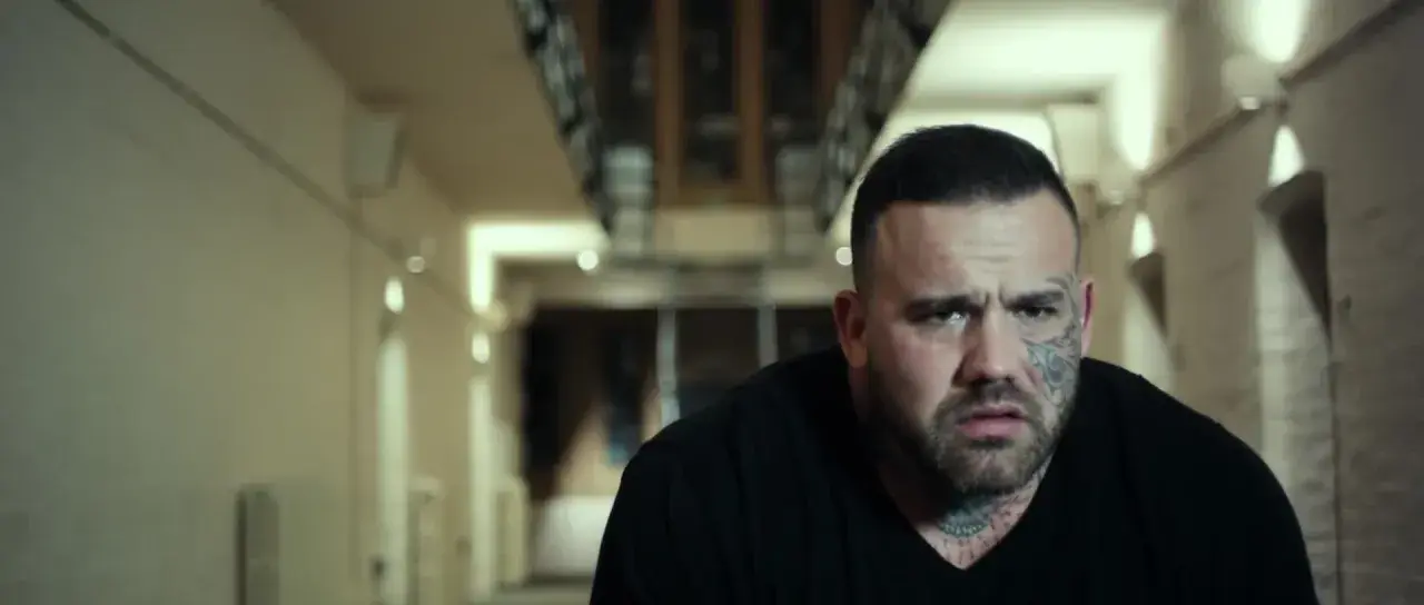 Martyn Ford, acteur aux multiples tatouages, dans un couloir sombre. Une scène qui pourrait figurer dans ses films.