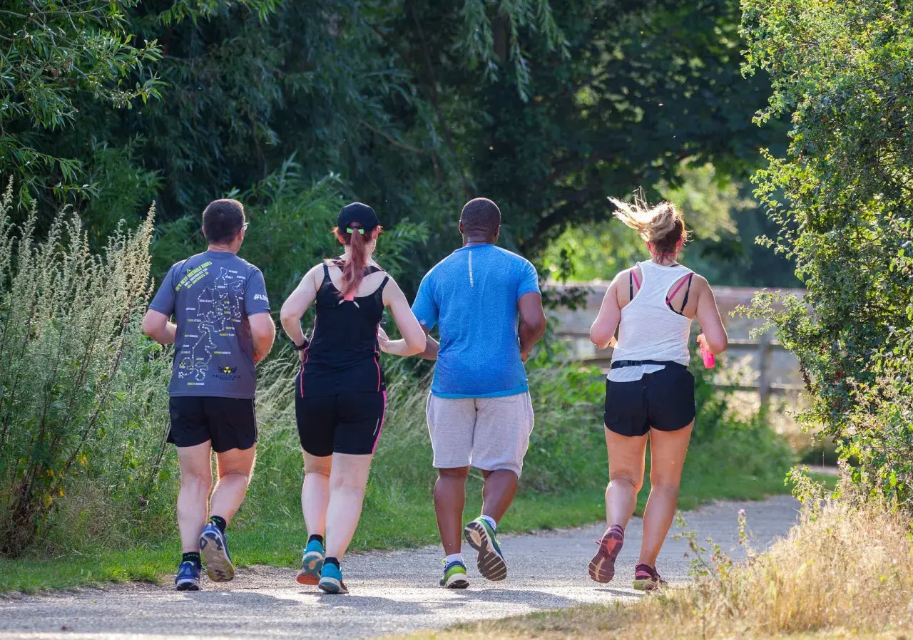 Quattro persone corrono su un sentiero. Ho perso 10 kg correndo, e loro sembrano motivati come me!