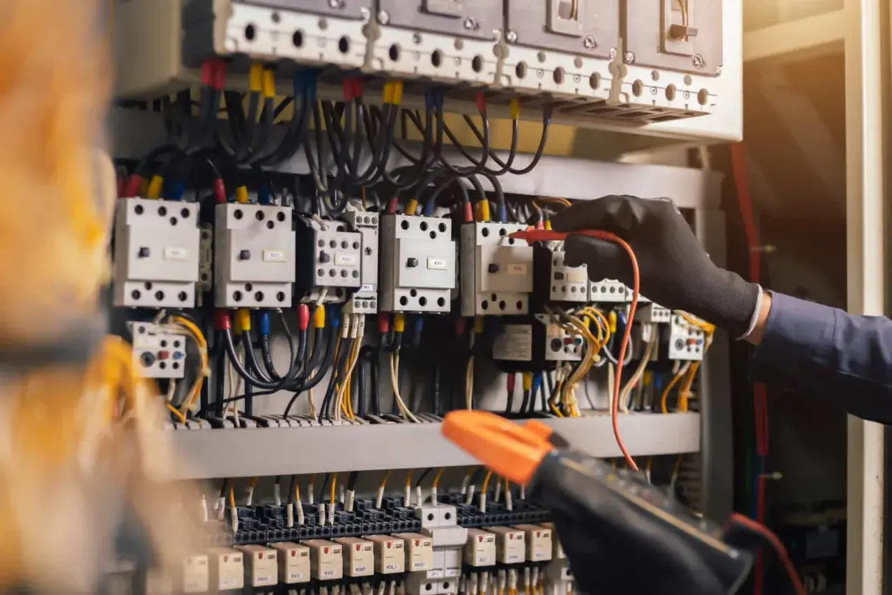 Main électrique d'une maison neuve, un technicien vérifie les connexions. Un devis électricité est essentiel pour ce type d'installation.