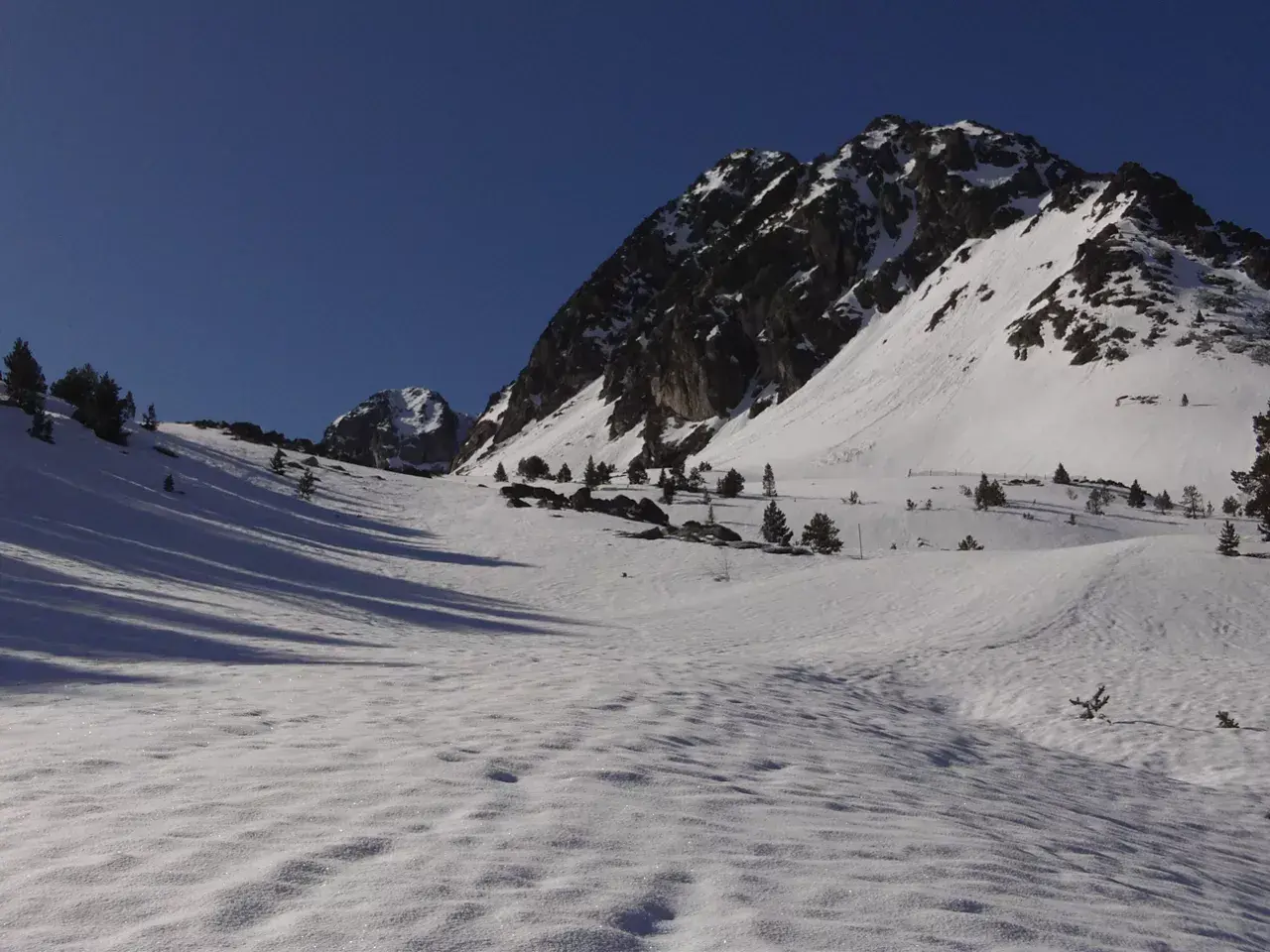 Paisaje invernal en Grau Roig, con montañas nevadas y cielo azul intenso.