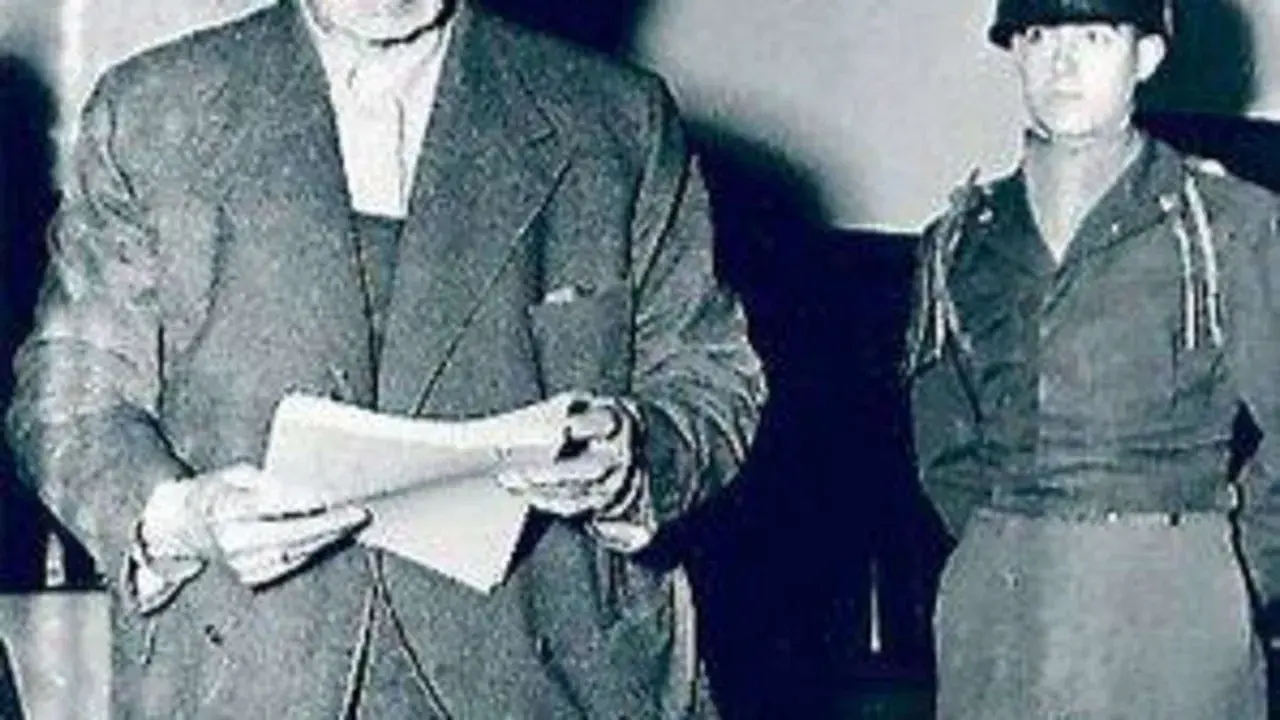 Ein Mann im Anzug hält Dokumente, daneben ein Soldat. Möglicherweise im Zusammenhang mit dem Flick-Konzern.