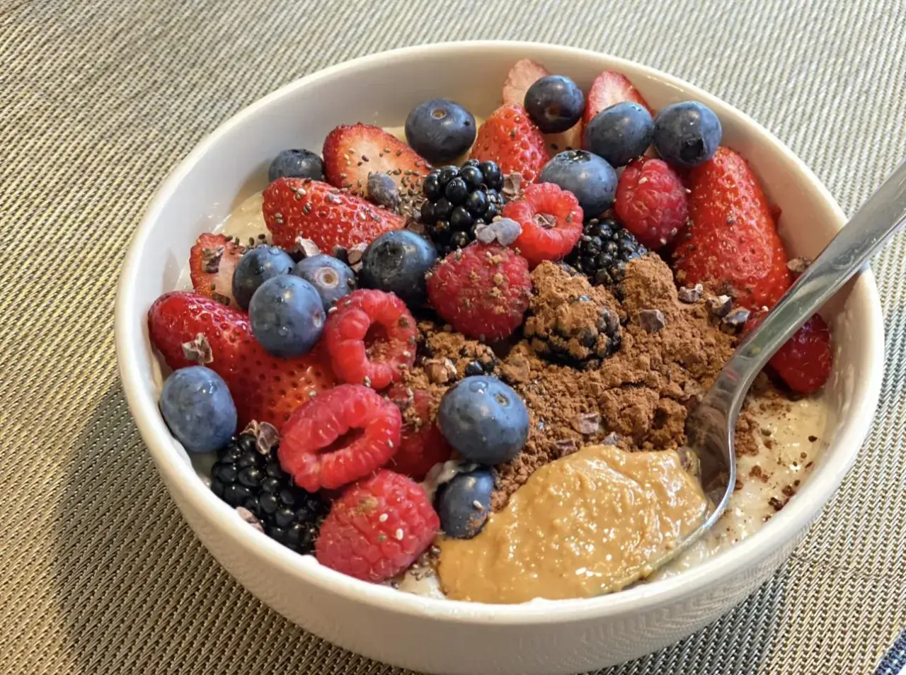 Schüssel mit overnight oats mit proteinpulver, Beeren, Kakao und Erdnussbutter.
