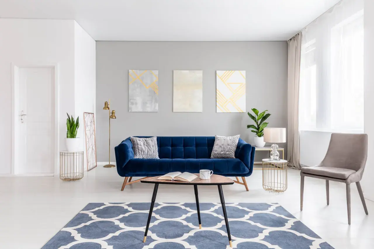 A stylish living room with a deep blue velvet sofa. Learn how to wash velvet to keep it looking luxurious.