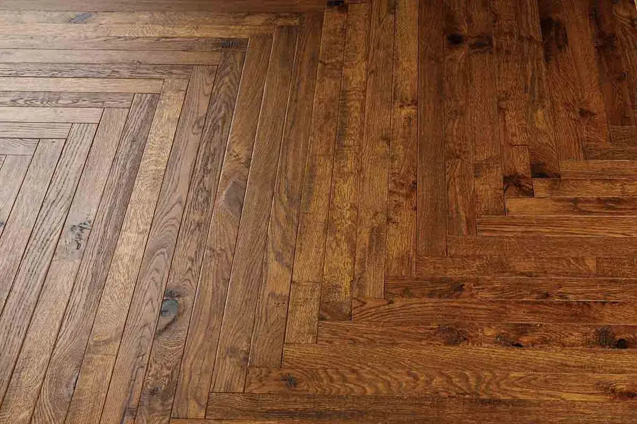 Dettaglio di un pavimento in legno con posa a spina di pesce. Valutare il parquet spina di pesce pro e contro per un tocco di classe.