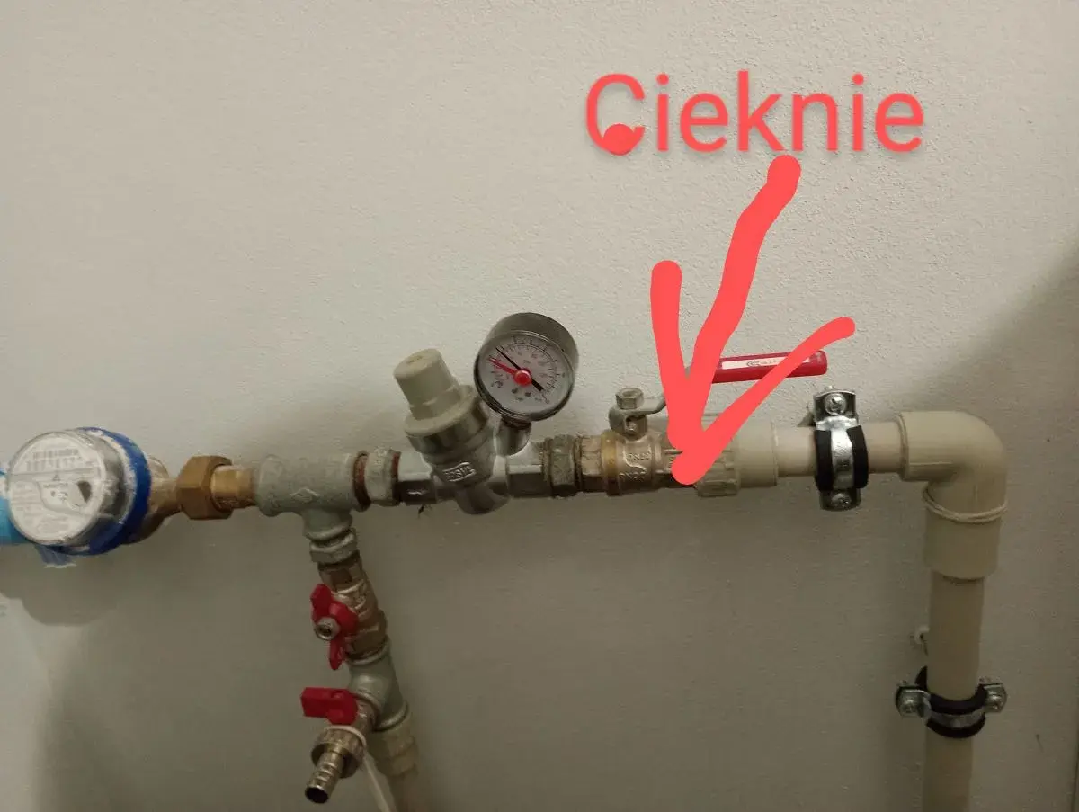 Cieknie zawór antyskażeniowy za wodomierzem. Czerwona strzałka wskazuje miejsce wycieku.