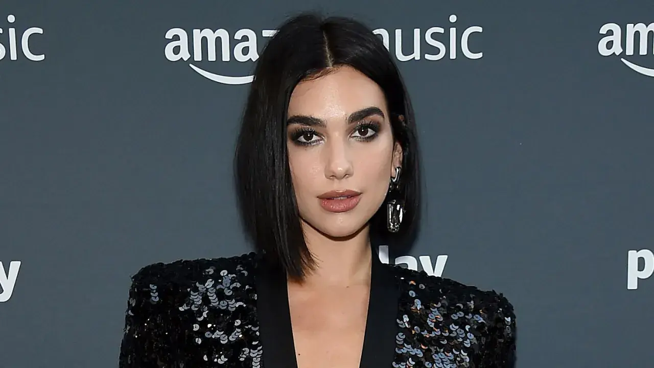 Mujer con un elegante corte pelo bob oscuro, maquillaje dramático y un blazer de lentejuelas.