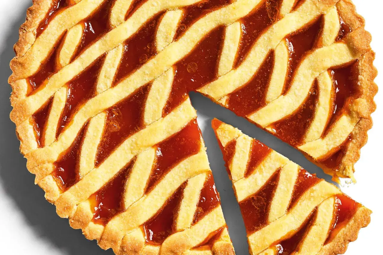 Torta con marmellata, la pasta frolla dorata e croccante è perfetta per la cottura. Due fette sono già state tagliate.
