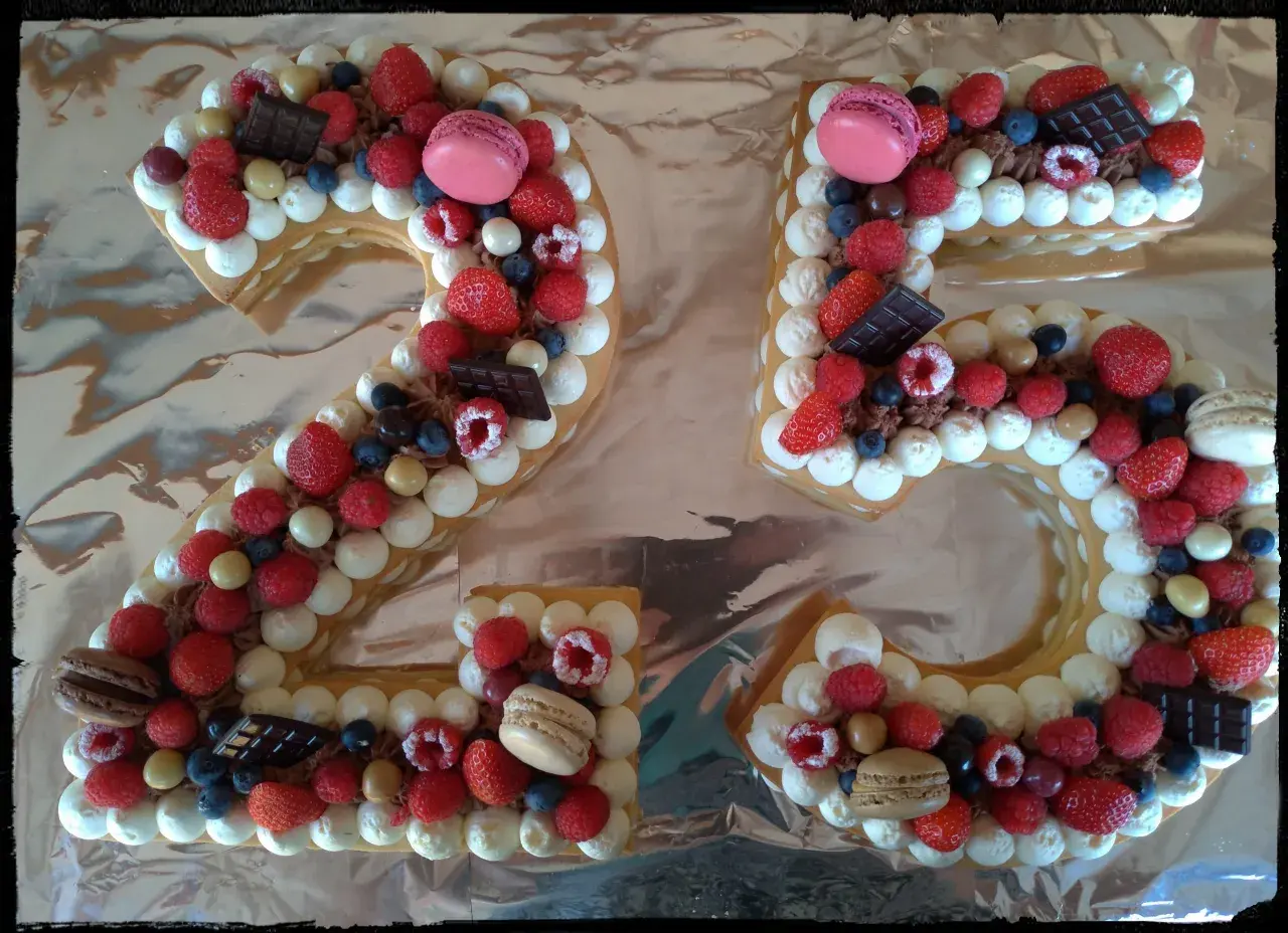 Gâteau chiffre 25 décoré de chantilly mascarpone, framboises, fraises, myrtilles, macarons et chocolat.
