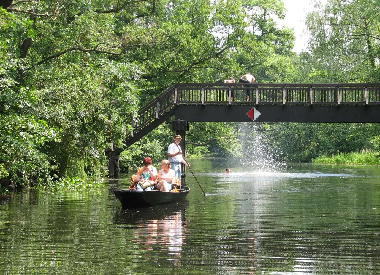 Bootsfahrt im Spreewald: Familie genießt die Natur, während jemand unter der Brücke schwimmt. Perfekte Ausflugsziele Spreewald für einen Sommertag.