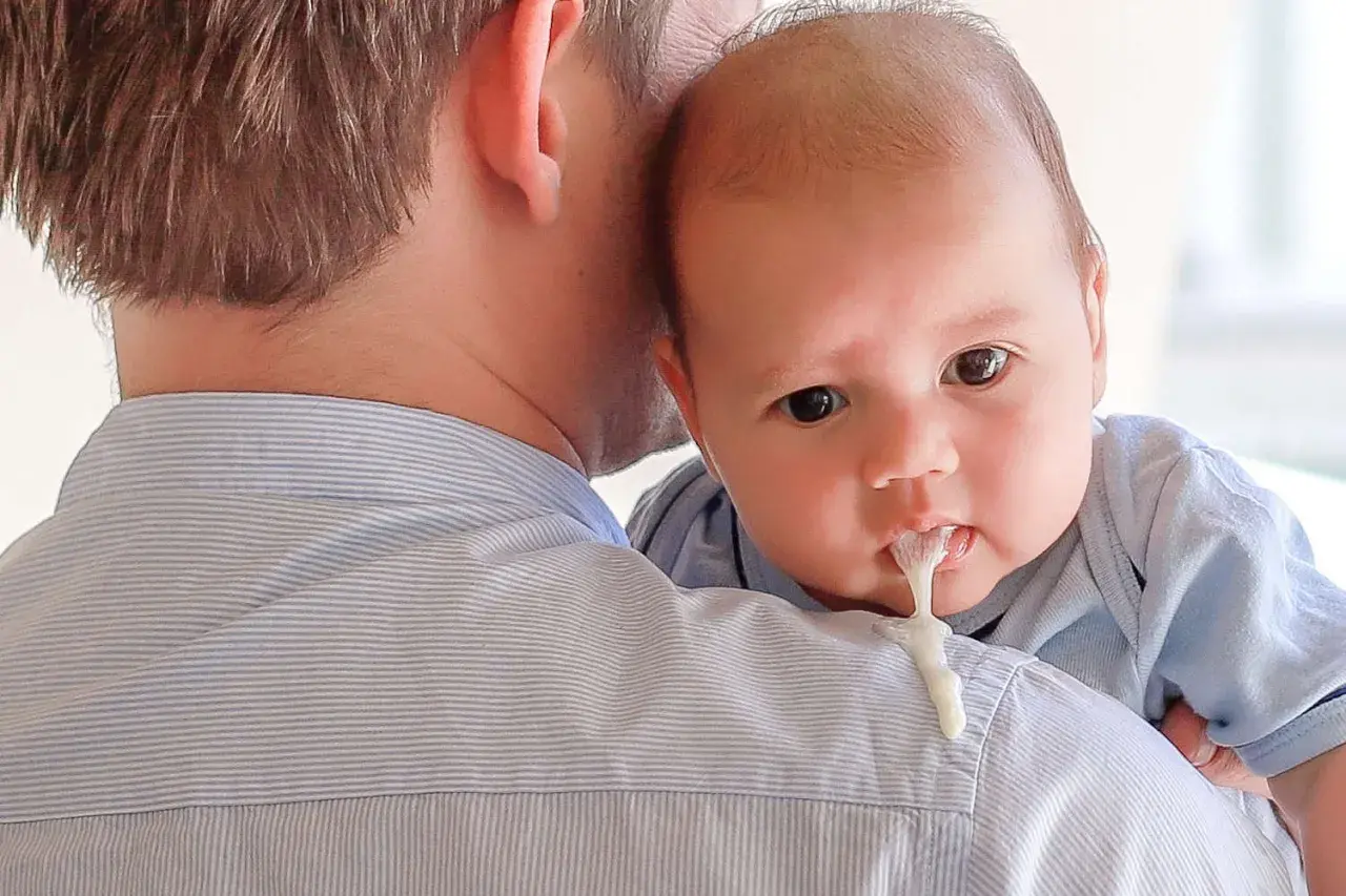 Neonato allattato al seno con reflusso, rigurgita latte sul pigiama del papà.