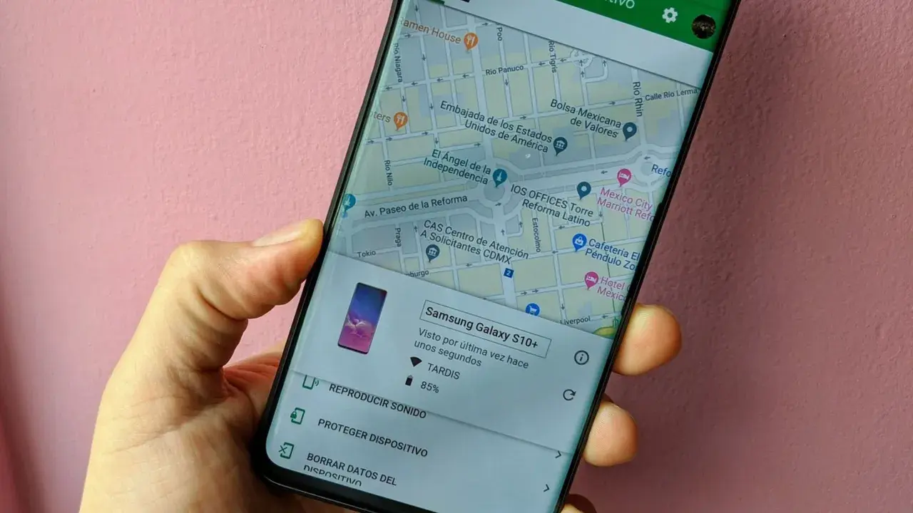 Mano sujetando un móvil que muestra la función de localizar móvil. Se ve un mapa de la Ciudad de México y opciones para reproducir sonido o proteger el dispositivo.