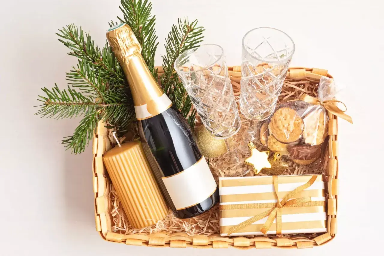 Festliche Fresskorb Ideen: Sektflasche, Gläser, Kerze, Kekse und Geschenk.