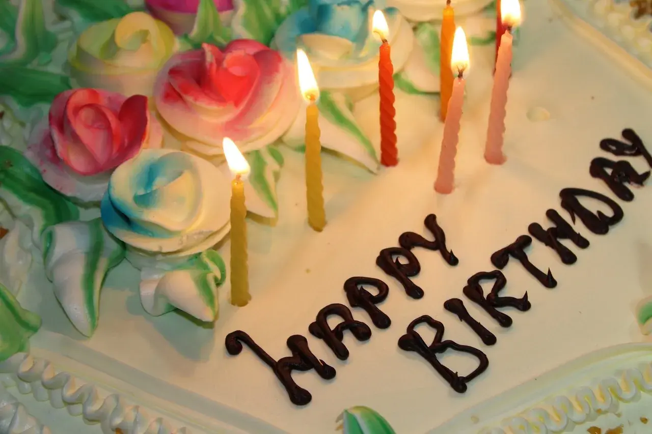 Pastel de cumpleaños con rosas de crema y velas encendidas. ¡Espero que estos textos de cumpleaños para mi novio largas hagan llorar de emoción!