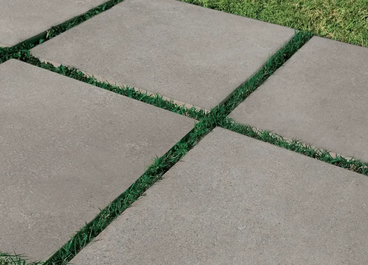 Percorso moderno con piastrelle da esterno 2 cm grigie, alternate a strisce di erba verde.