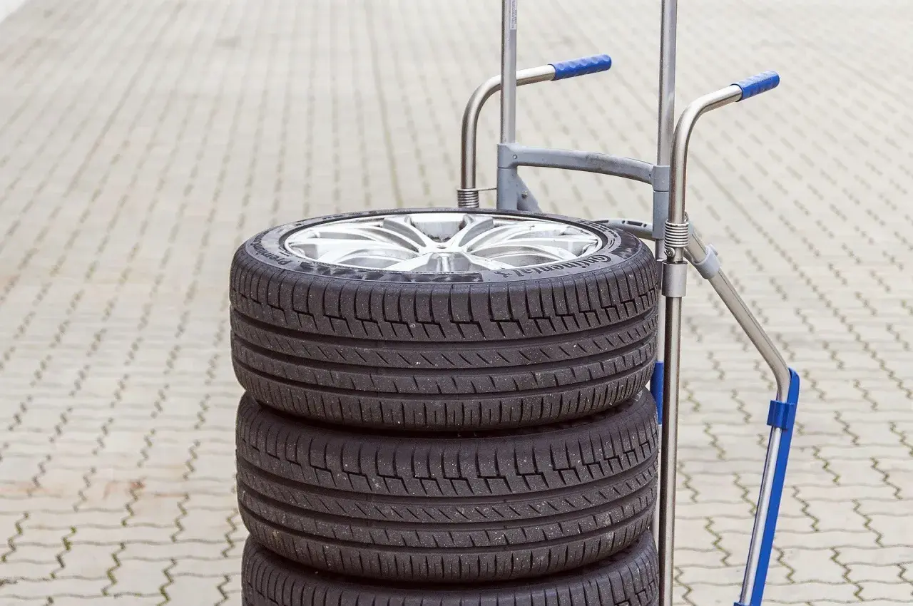 Stos czterech opon na wózku. Zastanawiasz się, ile waży opona? Ten zestaw jest gotowy do transportu.