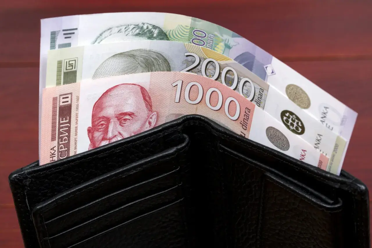 Czarny portfel wypełniony banknotami serbskie dinary. Widać nominały 1000 i 2000 dinarów.