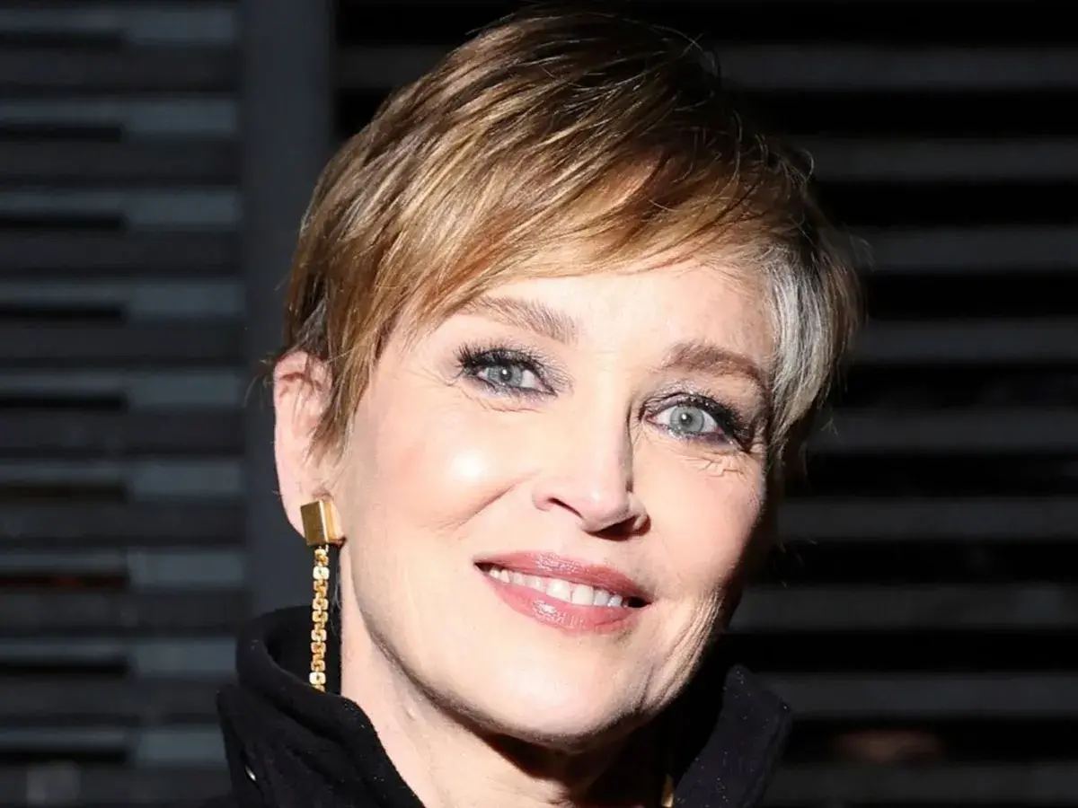 Señora sonríe con un moderno corte de cabello pixie, luciendo un elegante pendiente dorado.