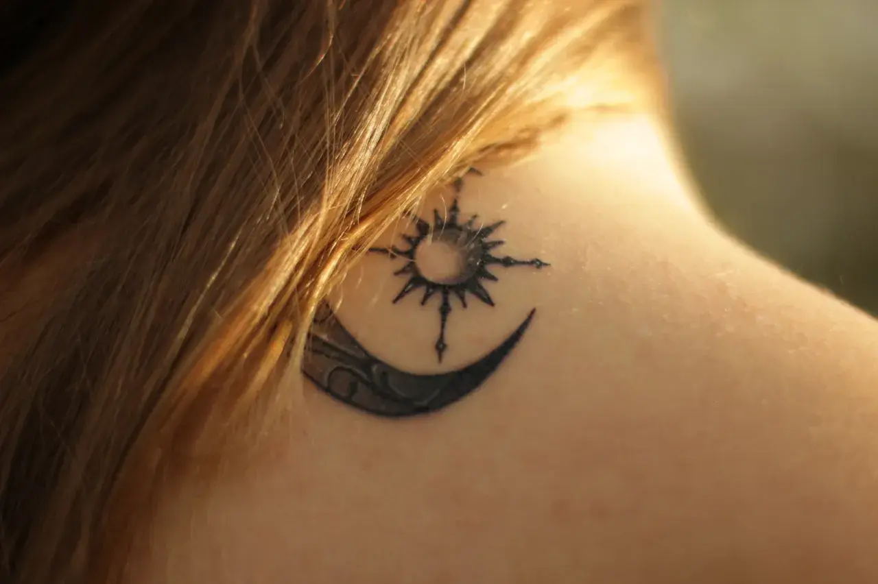 Tatouage lune et soleil sur la nuque, en phase de cicatrisation, une légère croûte est visible.